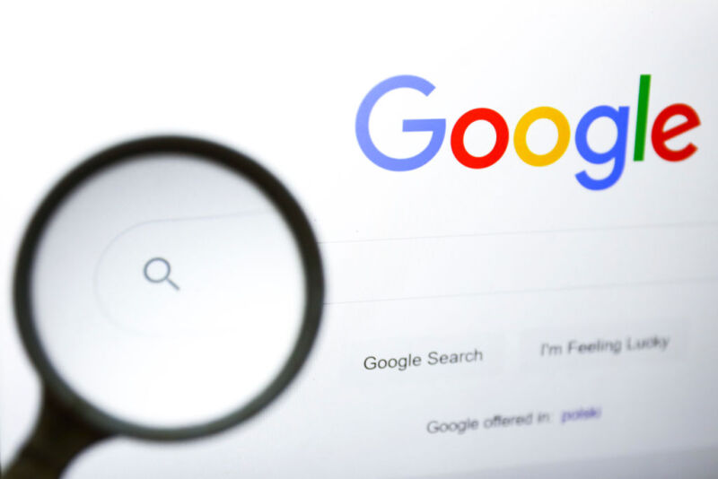 A magnifying glass is photographed with Google logo displayed
